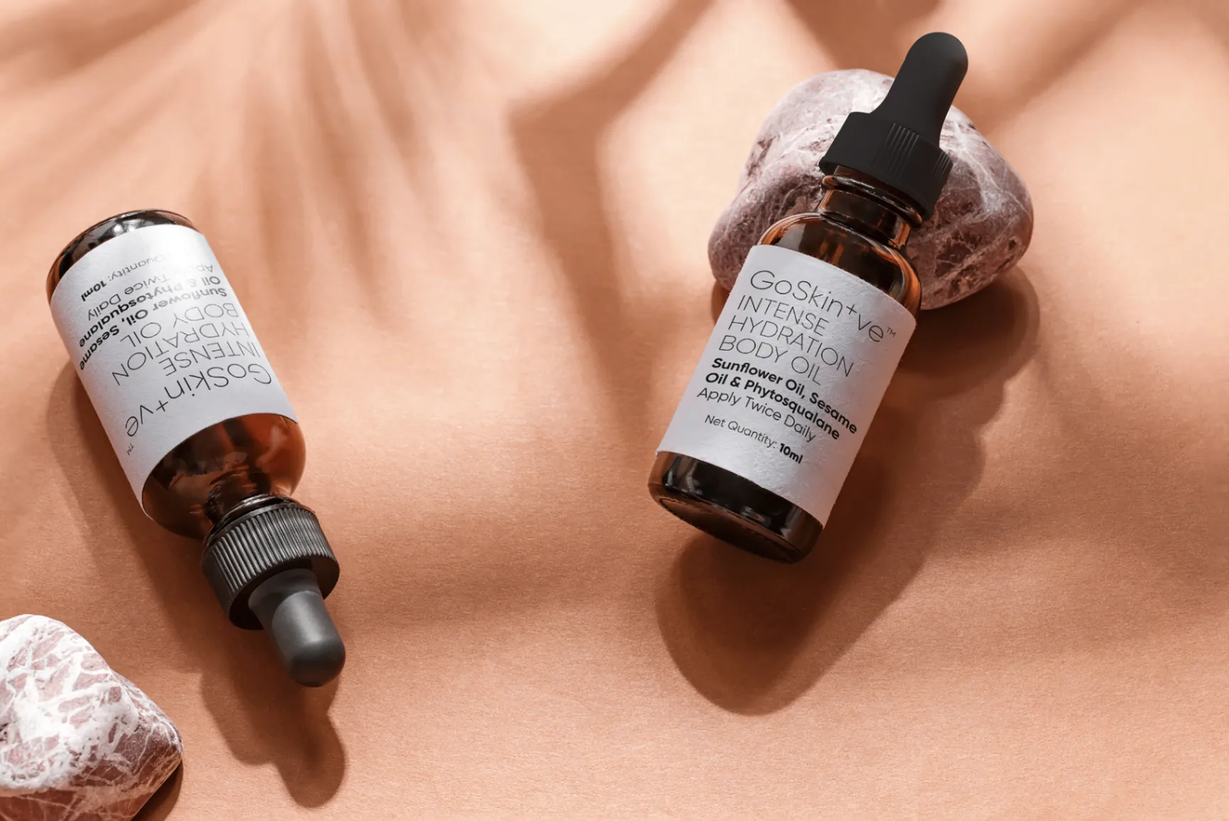 GoSkin+ve serums artistically arranged with droppers on warm stone background showcasing mindful skincare aesthetic