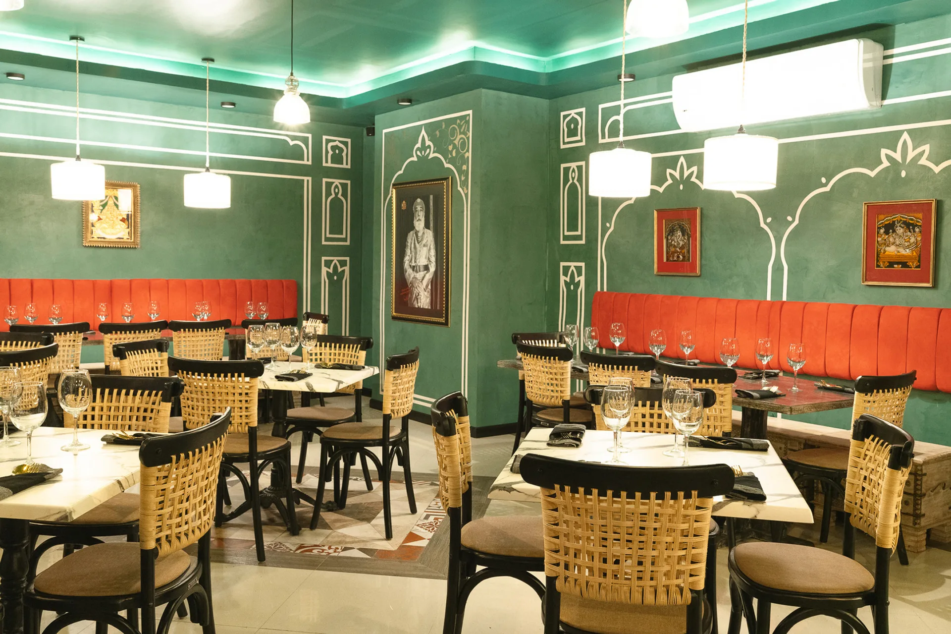 India Jones - Dining room with traditional Indian architectural elements, green walls, orange banquettes, and vintage Indian artwork
