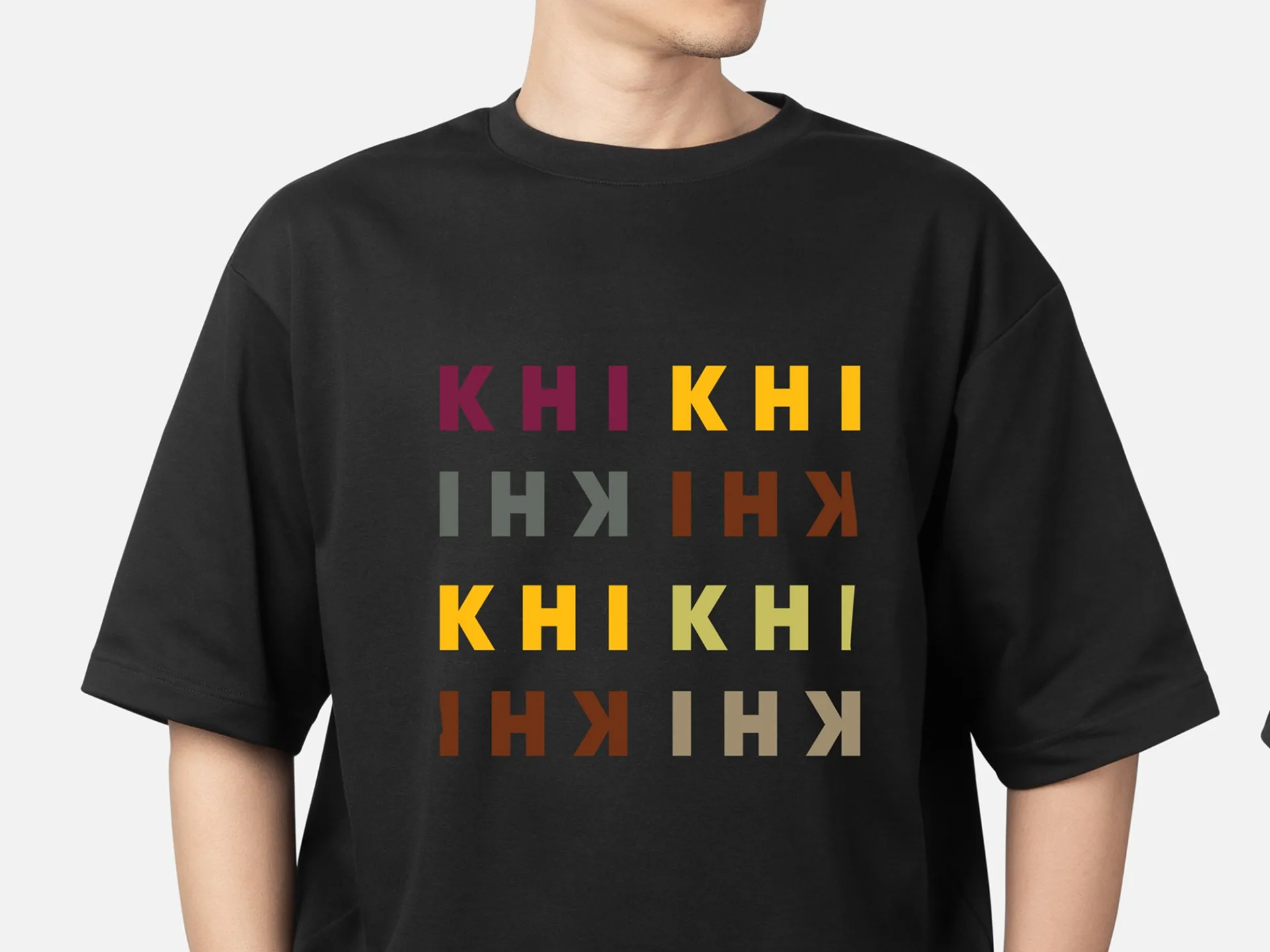 KHI KHI branded black t-shirt featuring multicolored logo variations in burgundy, yellow, olive, and brown tones